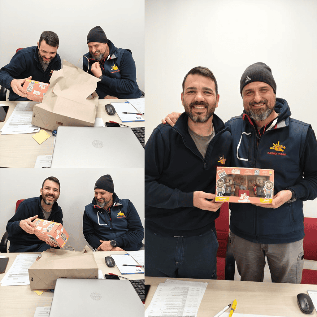 Due uomini sorridenti mostrano una scatola regalo di Natale in ufficio.