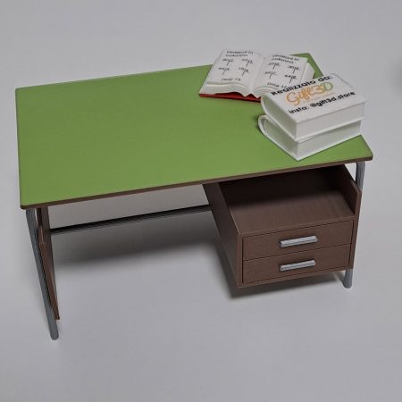 Scrivania con piano verde e cassetti marroni, con quaderno e libri sopra.