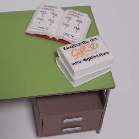 Miniature 3D-printed book and mug with Gift3D branding on green desk.