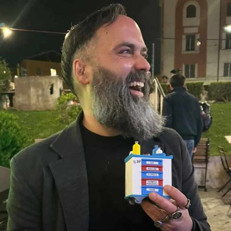 Persona sorridente con stampa 3D in mano, ambiente esterno serale.