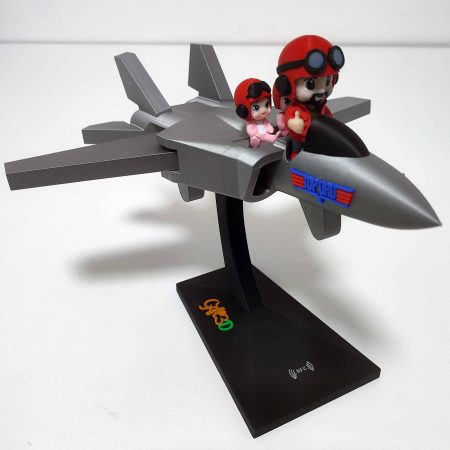 Modellino di aereo con personaggi in stile cartoon su base nera.